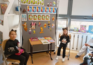 Dziewczynki oglądają biblioteczne zbiory książek z okazji Dnia postaci z bajek