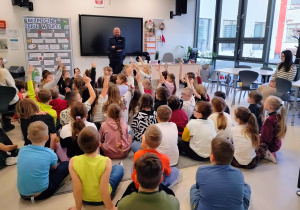 uczniowie aktywnie uczestniczą w prelekcji z policjantem