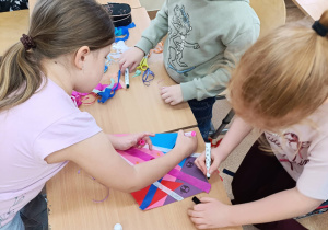 Dzieci w grupie ozdabiają latawiec