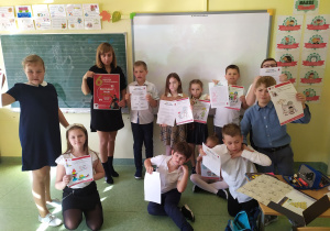 Dzieci pokazują rozwiązane krzyżówki i rebusy