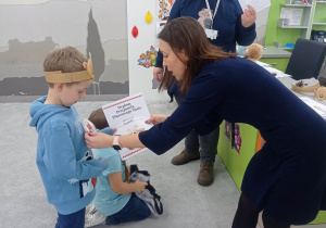 Nauczycielka wręcza uczniowi dyplom i medal.
