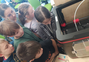 uczniowie przyglądają się wydrukowi 3D aniołków