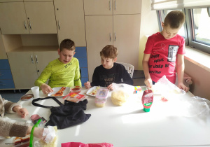 uczeń smaruje sosem pizzę