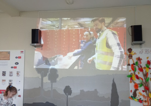 Uczniowie siedzą i oglądają film.