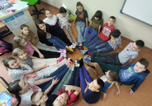 uczniowie siedząc w kole prezentują kolorowe skarpety