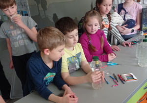 Uczeń obserwuje poruszającą się strzykawkę w butelce
