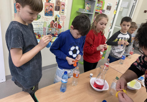 Uczniowie nakładają na butelkę balony