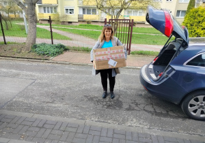 Nauczycielka wyciąga paczkę z samochodu.