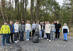 nauczycielka z uczniami stoją z workami śmieci