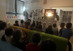 Uczestnicy zajęć oglądają teatrzyk cieni w bibliotece