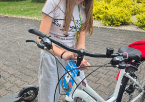 Uczennica przypinający numer startowy do roweru.