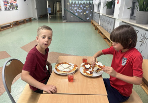 Chłopcy jedzą pizze