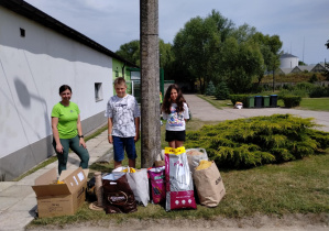 uczniowie wraz z opiekunką zwierząt stoją przed darami.