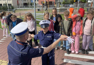 uczniowie poznają podstawowe gesty policjanta, który kieruje ruchem drogowym