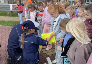mali policjanci rozdają wszystkim uczestnikom spotkania prezenty – odblaskowe kamizelki