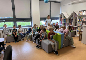 Uczniowie 1b na siedzą na pufach w czytelni.
