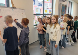 uczniowie na tablicy w sposób graficzny przedstawiają swój aktualny nastrój i emocje