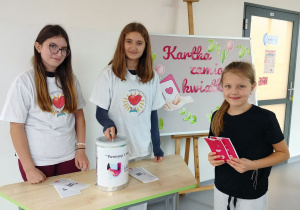 uczennica z wolontariuszami podczas zakupu cegiełek