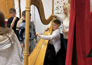 Chłopiec gra na harfie.