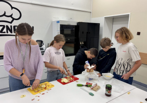 Uczniowie przygotowują ciasteczka z ciasta francuskiego.