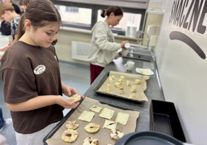 Uczennice układają ciasteczka na blaszce do pieczenia.