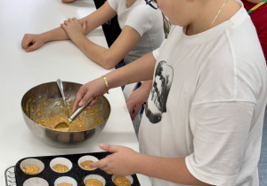 Uczeń przekłada ciasto do foremek.