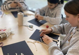 Dziewczynki wykonują drzewka z mchu i sznurka makramowego.