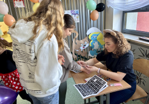 Dzieci w trakcie wykonywania brokatowych tatuaży.