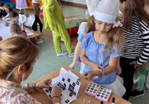 Pani Lucyna wykonuje brokatowy tatuaż dziewczynce.