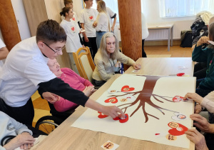 wolontariusz pomaga podopiecznym w wykonaniu pracy techniczno-plastycznej