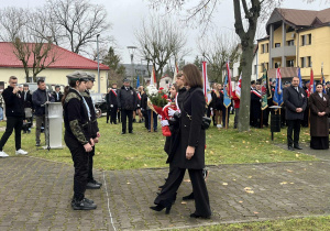 Pani Dyrektor wraz z asystą składa kwiaty pod pomnikiem.