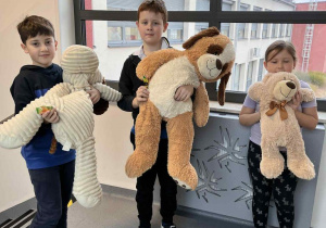 Uczniowie na szkolnym korytarzu z misiami