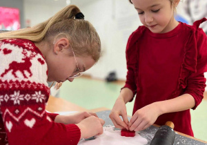 Dziewczynki wykrawają swoje pierniczkowe ozdoby.