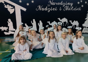 urocze aniołki pozują na tle stajenki