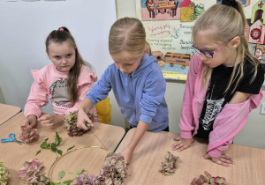 Dziewczynki tworzą jesiennie wianki.