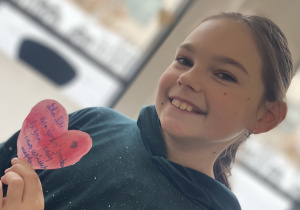 Uczennica pokazuje serduszko z miłymi zwrotami do koleżanki.