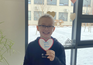 Chłopiec pokazuje serduszko z miłymi zwrotami do kolegi.