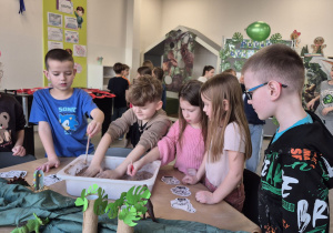 Dzieci podczas zabawy w paleontologa z wykorzystaniem masy sensorycznej.