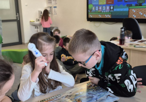 Uczniowie słuchają ciekawostek o dinozaurach z interaktywnej książki Albik.