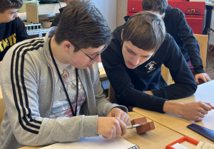 Uczniowie wykonują pomiar suwmiarką.