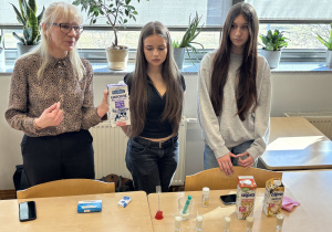 Nauczycielka z uczennicami wyjaśnia doświadczenie.