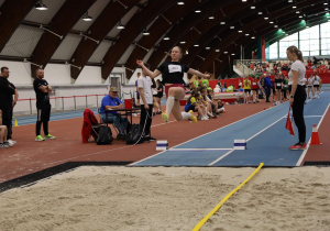 Uczennica w trakcie konkurs skoku w dal.