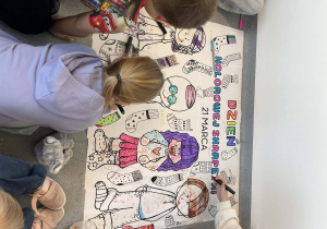 dziewczynki malują tematyczną kolorowankę z okazji Dnia Kolorowej Skarpetki