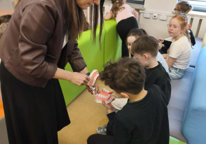 Uczniowie przy pomocy modelu ćwiczą poprawne szczotkowanie zębów