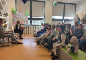 Przedszkolaki z uwagą słuchają bajki czytanej przez bibliotekarkę