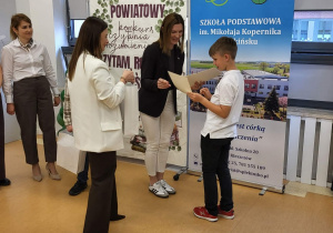 Pani dyrektor wręcza dyplom i gratulacje dla chłopca
