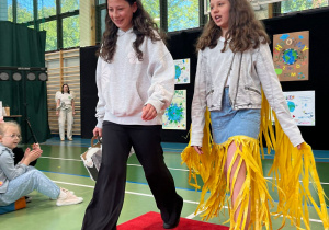 Uczennice klasy piątej prezentujące elementy garderoby wykonane z kartonów i plastiku