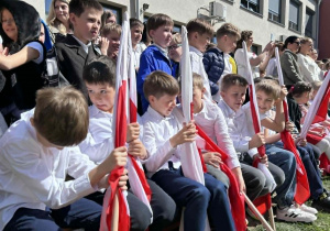 Uczniowie trzymają flagi i oczekują na swój występ
