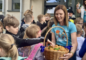 Pani dyrektor rozdaje uczniom słodki upominek