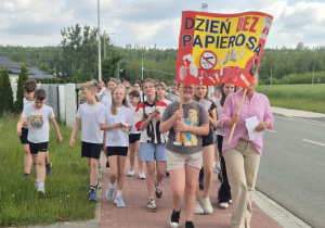 nauczyciel wraz z uczniami niesie transparent podczas ulicznego happeningu